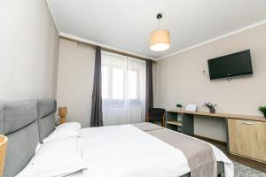 a bedroom with a bed and a desk and a television at Residence Piata Sfatului in Braşov