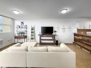 a living room with a white couch and a tv at Haudimar Beach Apt Ocean Front With Parking in San Antonio