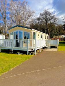 a small white house with a porch and a bench at Edinburgh Lux Lodge Seton Sands in Port Seton