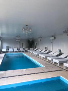 a swimming pool with white chairs and a blue pool at Complejo Aquiles in Lobos