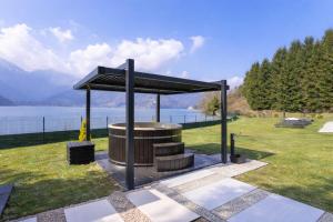 a picnic shelter in a park next to a body of water at Villa Ledro with Private Dock - Sauna - Hot Tub in Molina di Ledro