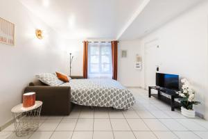a bedroom with a bed and a couch and a tv at Le Carnot Garden in Étampes