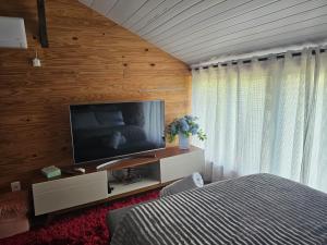 a bedroom with a bed and a flat screen tv at Casa Aconchegante in Pomerode
