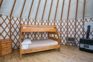 a wooden bunk bed in a yurt with a stove at Yosemite Lakes Yurts in Harden Flat