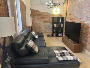 a living room with a leather couch and a television at Casa Balcones in Sahagún