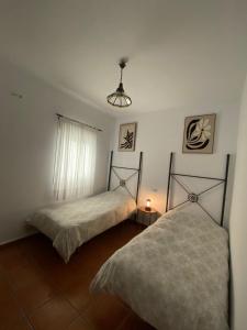a bedroom with two beds and a lamp on the floor at Apartamento Tarramilla in Prado del Rey
