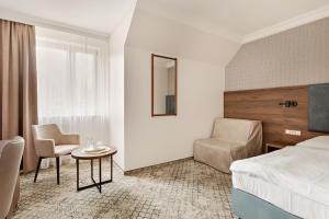 a hotel room with a bed and a chair and a table at Hotel Sylwia in Sośnicowice