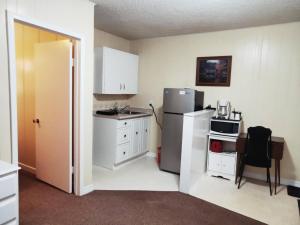 a small kitchen with a refrigerator and a table with a chair at Melsask Motel in Melville