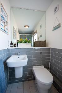 a bathroom with a sink and a toilet and a mirror at Pine Cones in Rhoscolyn +32 photos