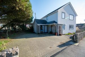 a white house with a driveway in front of it at Pine Cones in Rhoscolyn