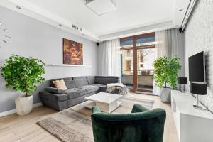 a living room with a couch and a tv at Wilanów Cinema Apartment in Warsaw