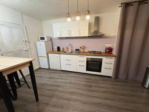 a kitchen with white cabinets and a table and a stove at Appartement la Tûte centre Laruns in Laruns +2 photos