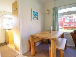 a dining room with a wooden table and a window at Chalet 23 Erw Porthor in Tywyn