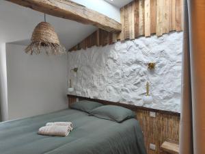 a bedroom with a bed with a stone wall at Escale à Clisson - Les jardins de Bali in Clisson