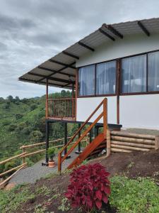 a house with a balcony on top of a hill at eco hotel finca los naranjos in Salento