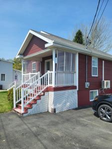 a red house with a white porch and stairs at Nice and cozy in Dalhousie