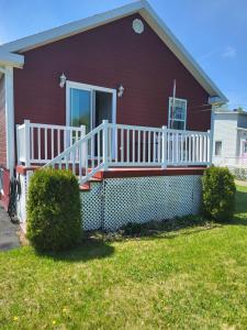 a red house with a white railing on a porch at Nice and cozy in Dalhousie +10 photos