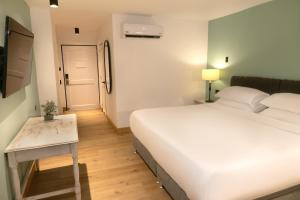 a bedroom with a large white bed and a table at Hotel Faranda Express Puerta Del Sol Barranquilla, A Member of Radisson Individuals in Barranquilla +71 photos