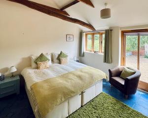 a bedroom with a large bed and a chair at Avocet Cottage in Dunwich