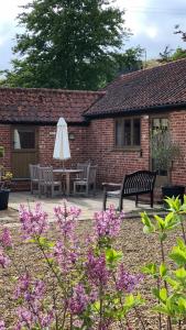 a patio with a table and an umbrella and flowers at Avocet Cottage in Dunwich