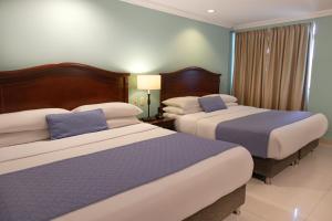 two beds in a hotel room with blue walls at Hotel Faranda Express Puerta Del Sol Barranquilla, A Member of Radisson Individuals in Barranquilla