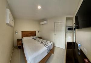 a small bedroom with a bed and a tv at Hotel Baja in Tijuana