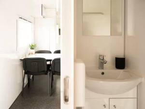 a bathroom with a sink and a table with chairs at Budget Mobile House in Faroe Islands in Strendur