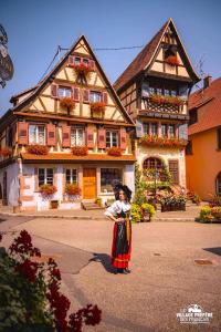 a little girl standing in front of a building at L'Etoile du Vignoble Meublé de Tourisme 4 étoiles au cœur d'un ranch alsacien sur la route des Vins - Climatisé in Dambach-la-Ville