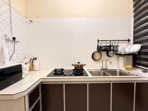a kitchen with a sink and a stove at Qisa Guesthouse 03 in Arau
