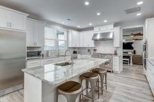 a kitchen with white cabinets and a large island with bar stools at The Flamingo Place in Rockport