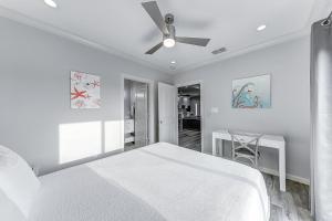 a white bedroom with a bed and a ceiling fan at The Flamingo Place in Rockport