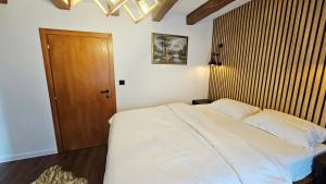 a bedroom with a white bed and a wooden door at Apartments Kenan in Plav