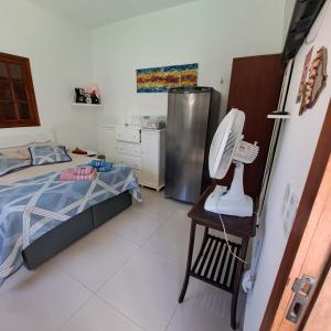 a bedroom with a bed and a chair with a fan at Charmosa suíte de Tucuns. in Búzios