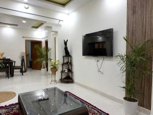a living room with a tv on a white wall at Palm Stone Villa in Lucknow
