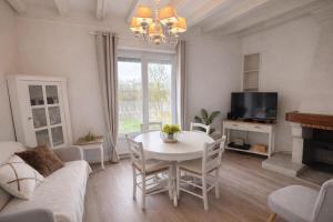 a living room with a white table and a tv at Le Petit Nid de Beauval in Saint-Aignan