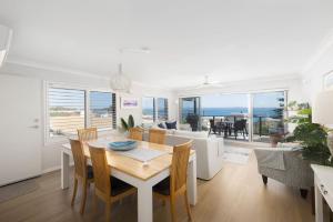 a dining room and living room with a table and chairs at Sundeck Shoal Bay Ground floor with views and pool access in Shoal Bay