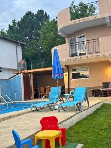 a group of chairs and an umbrella next to a pool at Helena Guest House - Pool & Sea View in Balchik