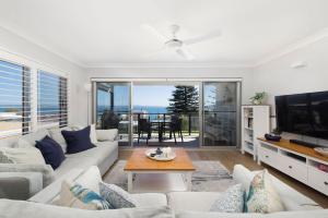 a living room with a couch and a tv at Sundeck Shoal Bay Ground floor with views and pool access in Shoal Bay