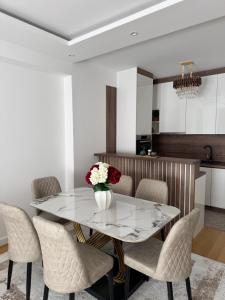 a dining room table with chairs and a vase of flowers at Moderan 80m2 apartman - 2 kupatila - terasa - blizu centra i plaze in Bar