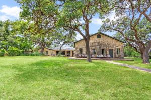 a stone house with trees in front of a yard at Live Oak Ranch in Spring Branch