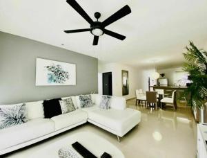 a living room with a white couch and a ceiling fan at Grand Blue Playa in Playa del Carmen