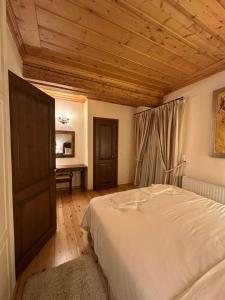 a bedroom with a white bed and a wooden ceiling at Nostalgia Guesthouse Arachova in Arachova