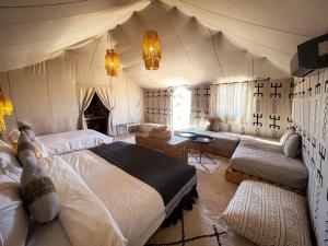 a bedroom with a large bed and a couch at dreaming desert Luxury Camp in Adrouine