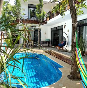 a swimming pool in front of a house with a tree at Villa Tucanes in Tulum