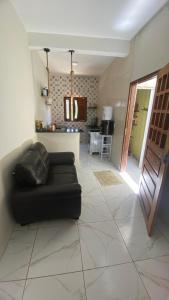 a living room with a black couch and a kitchen at Casa Aconchego in Japaratinga +16 photos