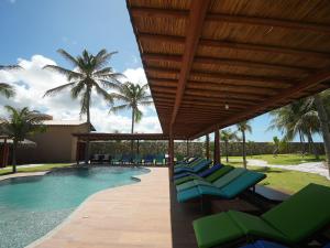 a pool with green lounge chairs and palm trees at Beachfront Studio with Pool Caponga in Cascavel
