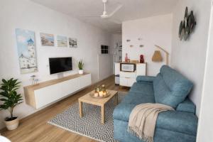 a living room with a blue couch and a tv at Brisa al Mar in Bellreguart