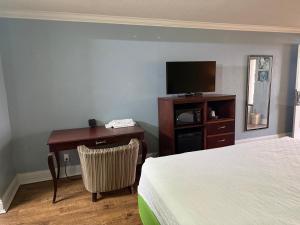 a hotel room with a bed and a desk with a television at Soho inn & suites in Perry