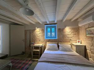 a bedroom with a bed and a stone wall at Stasa Aegina in Egina