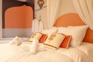 a bed with orange and white pillows and a tub at Marrakech Cinéma Jacuzzi - Suite romantique in Feyzin